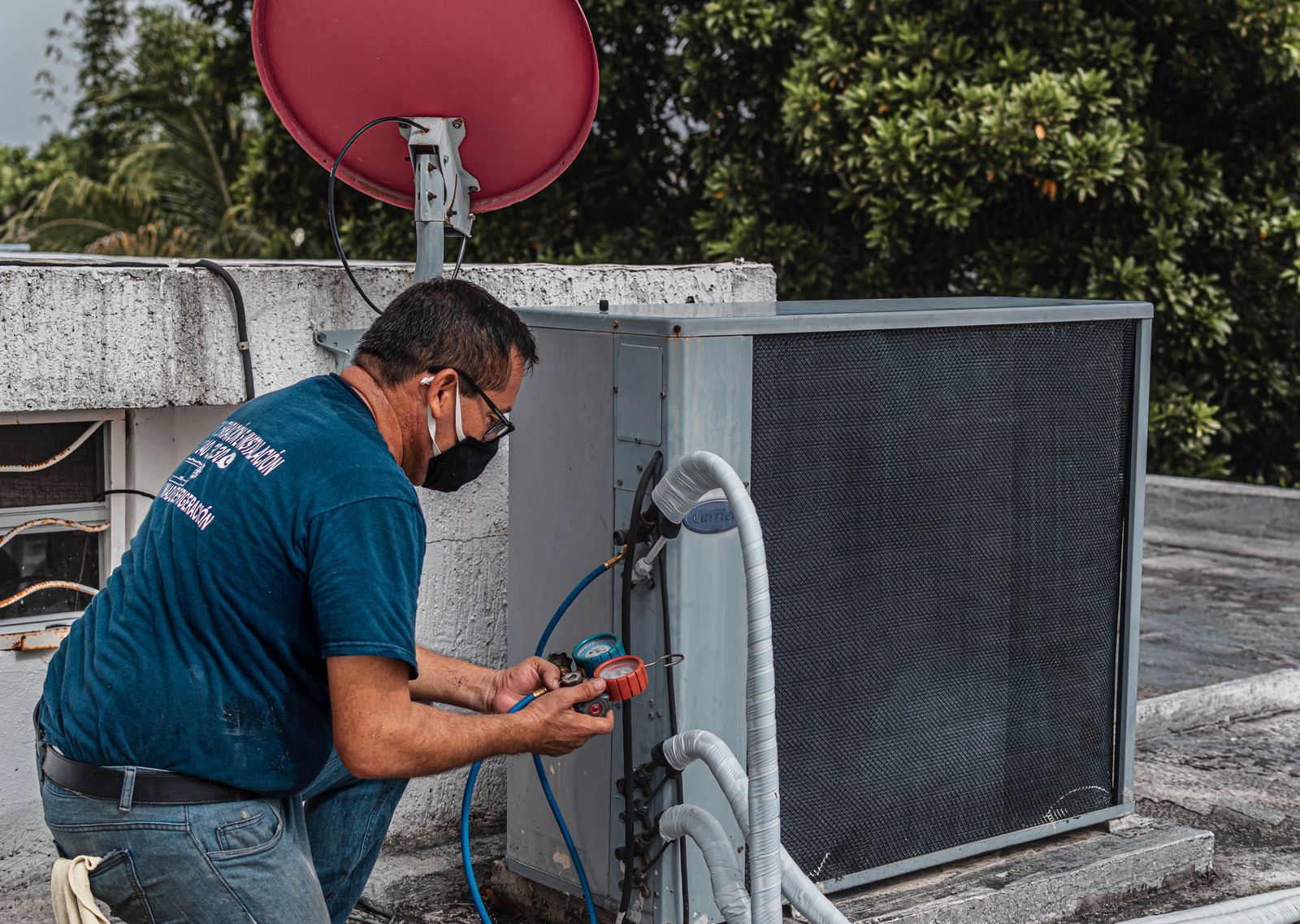 A technician checking and cleaning an outdoor air-conditioning unit