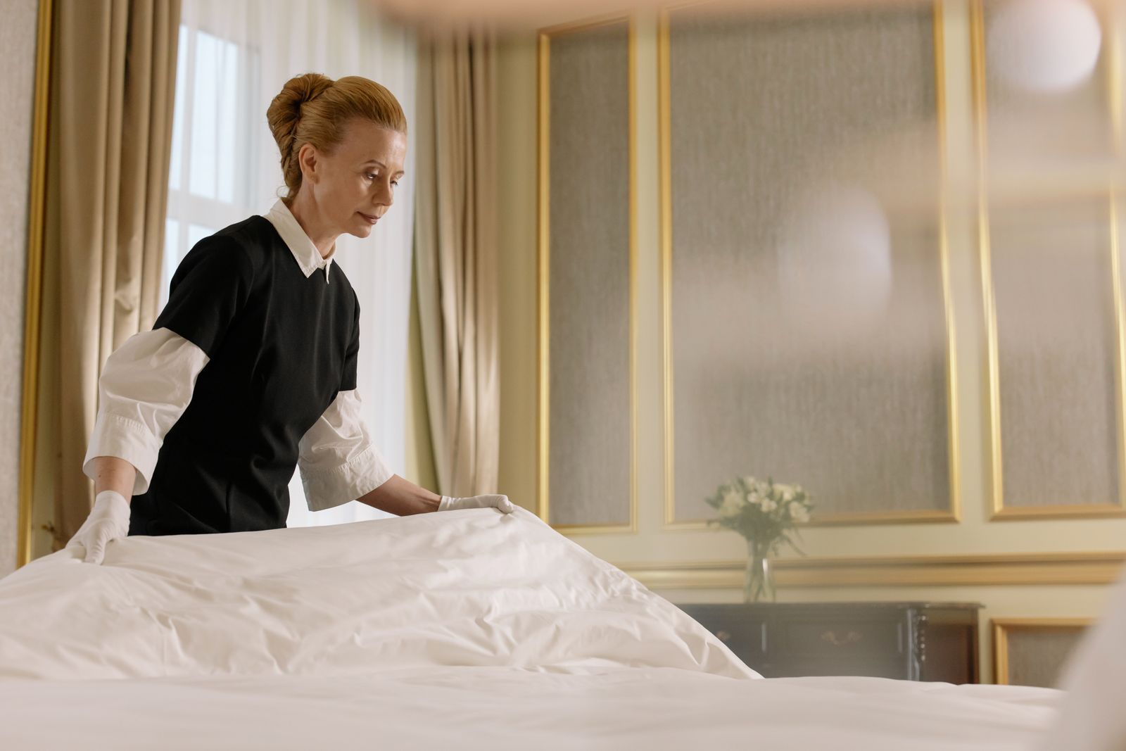 A professional housekeeper making a bed with fresh linen
