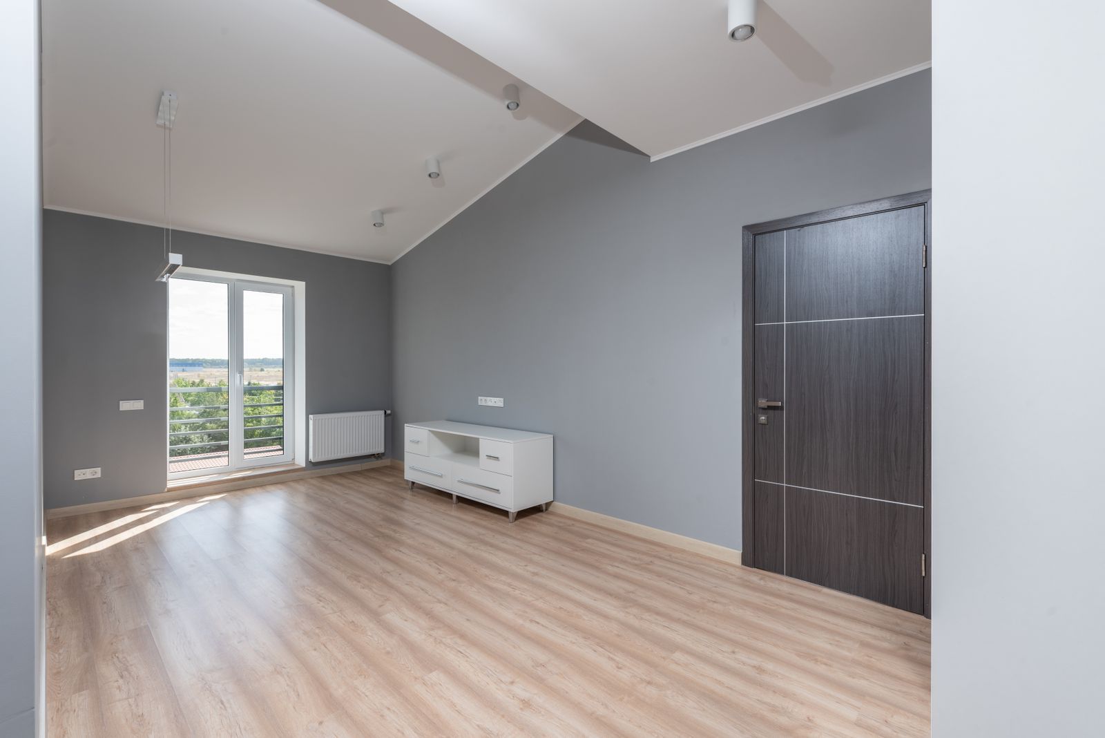 A clean empty room with wooden floors and large windows, ready to move into