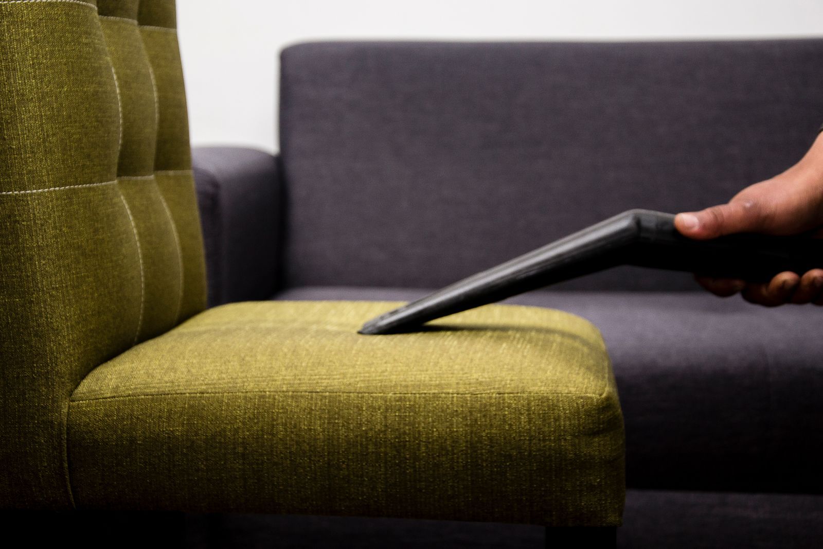 Close-up of a sofa being vacuumed to lift dust out of the fabric